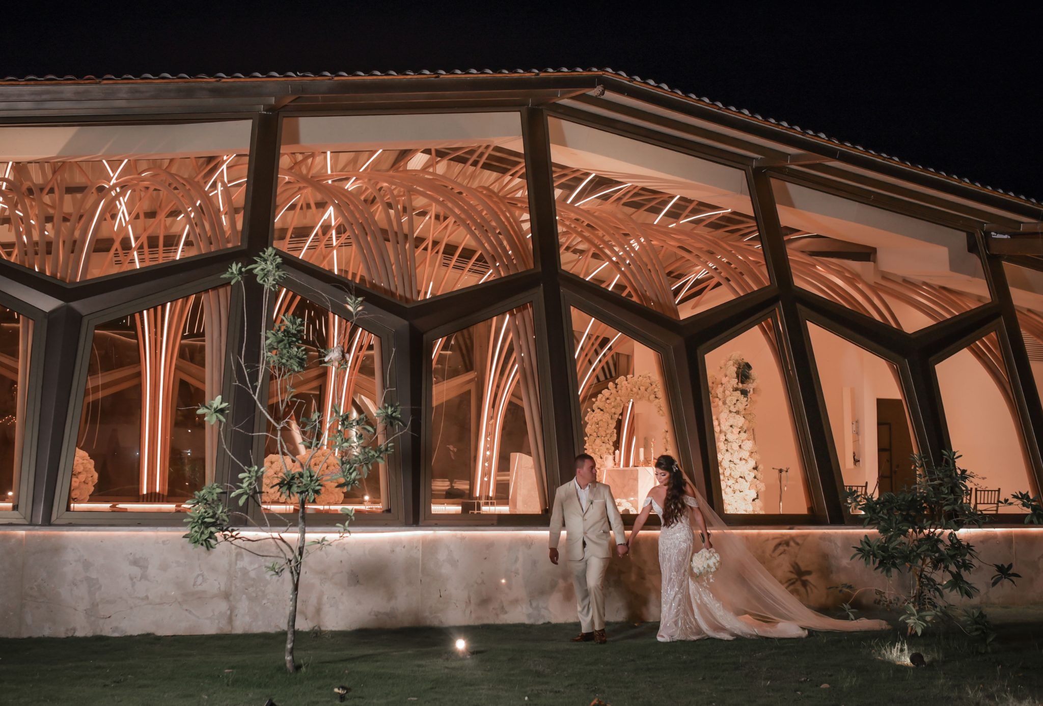 Pareja de novios frente a la capilla y el salón iluminados de noche
