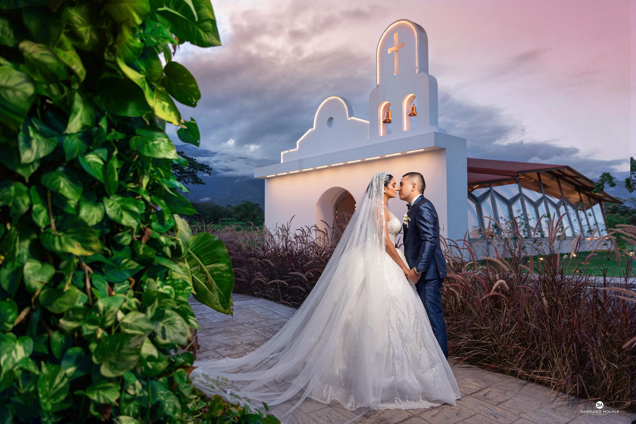 Pareja de novios frente a la capilla iluminada de Hacienda Las Marías al atardecer
