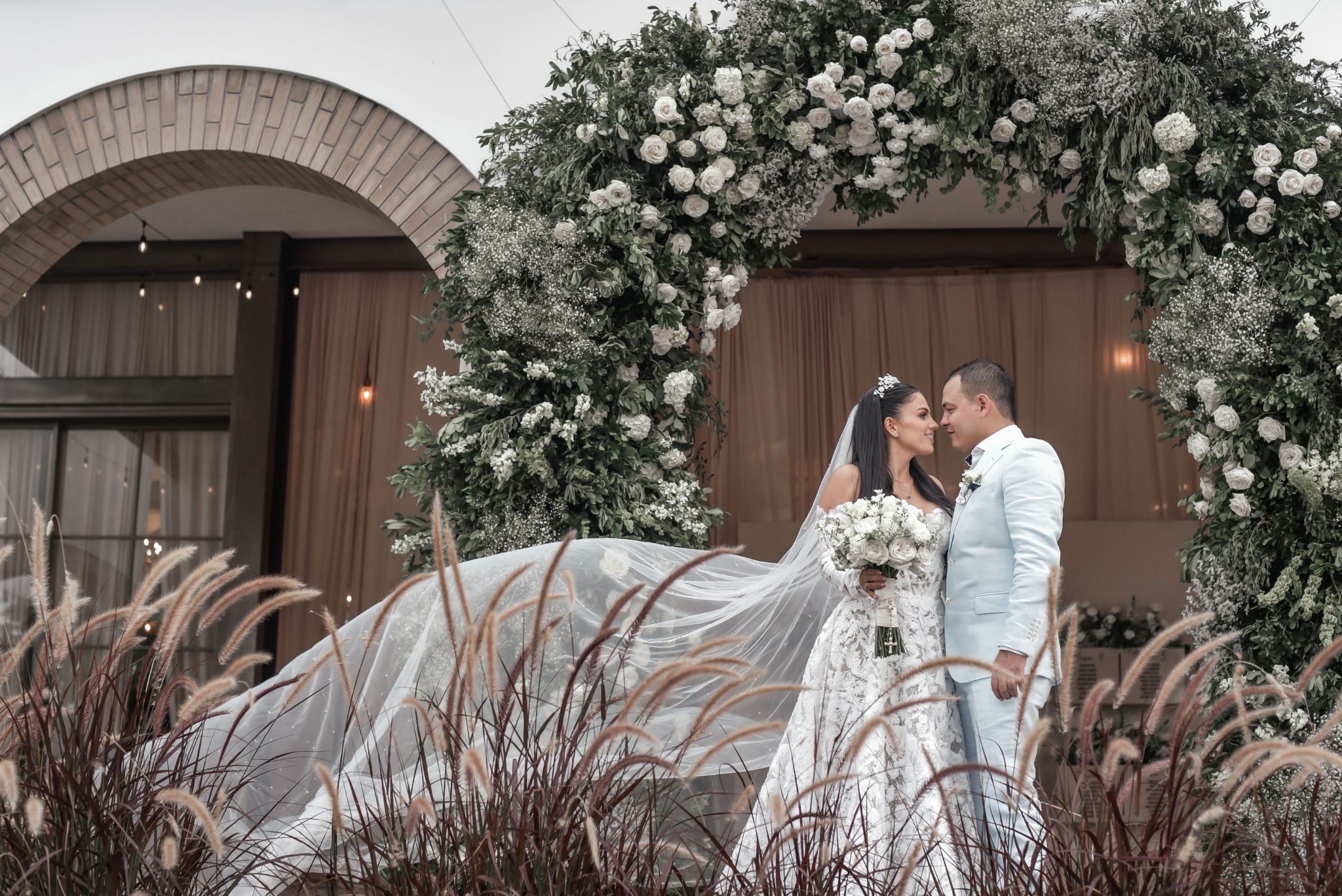 Novios bajo el arco floral blanco